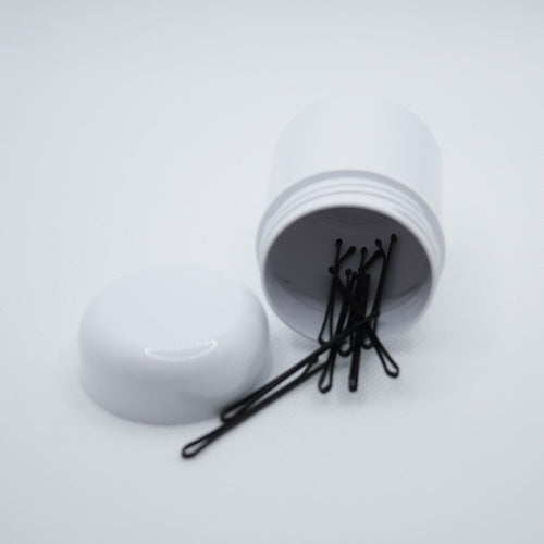 Boião branco de 50 ml com tampa, com alfinetes pretos visíveis dentro. Reciclável e reutilizável.